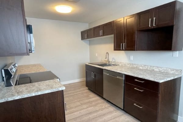 An empty kitchen with brown cabinets and stainless steel appliances.