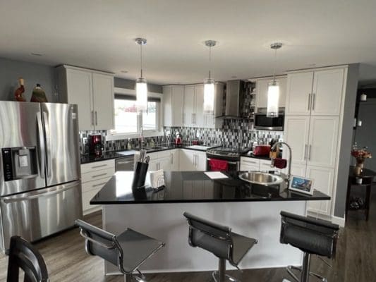 A kitchen with black and white counter tops and stools.