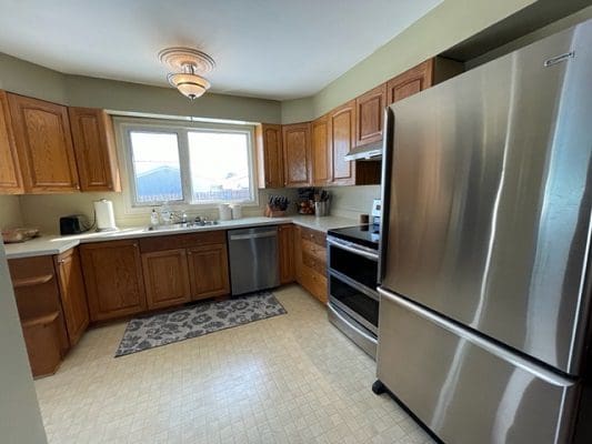 A kitchen with stainless steel appliances and wooden cabinets.