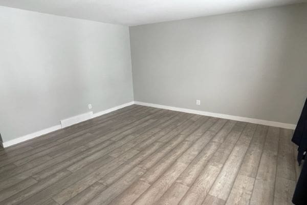 An empty room with wood floors and gray walls.