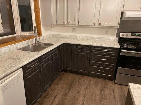 A kitchen with white cabinets and marble counter tops.