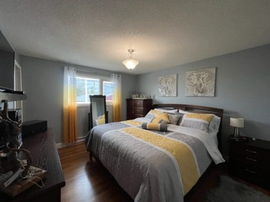 A bedroom with hardwood floors and a yellow comforter.