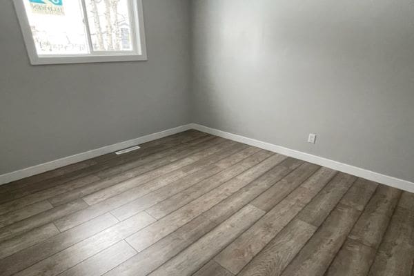 An empty room with wood floors and a window.