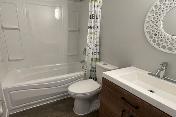 A bathroom with a toilet, sink and shower.