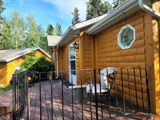 A cabin in the woods with a deck and railing.