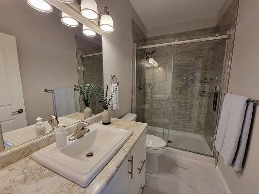 A bathroom with marble counter tops and a walk in shower.