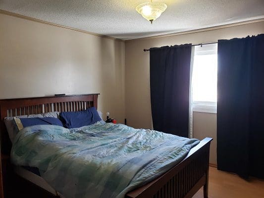 A bedroom with a blue comforter and a window.