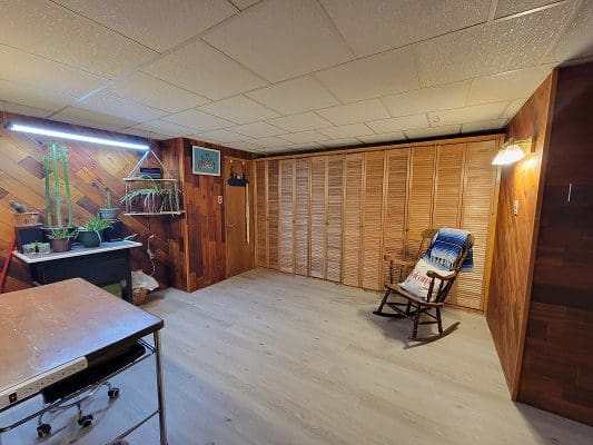 An empty room with wood paneling and a rocking chair.