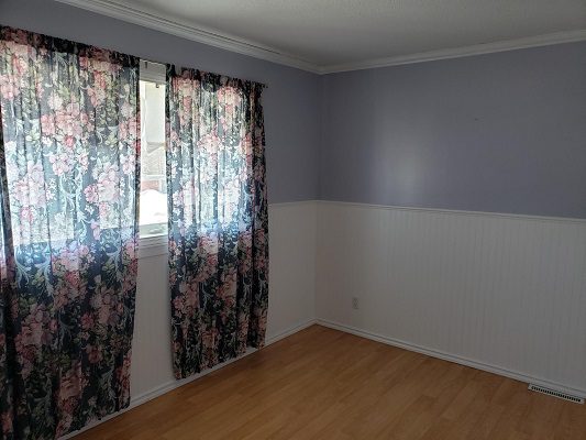 An empty room with purple curtains and hardwood floors.