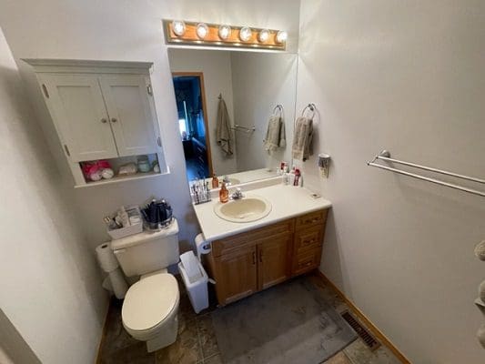 A bathroom with a toilet, sink and mirror.