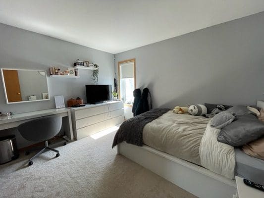 A bedroom with a bed, desk and tv.
