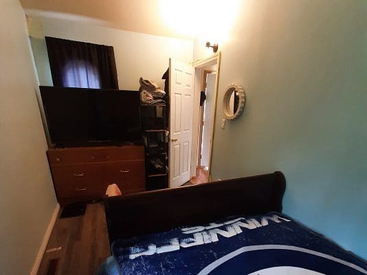 A bedroom with a bed, dresser and tv.