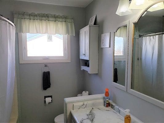 A bathroom with a sink, toilet and mirror.