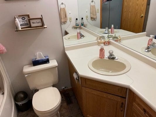 A bathroom with a toilet, sink and mirror.