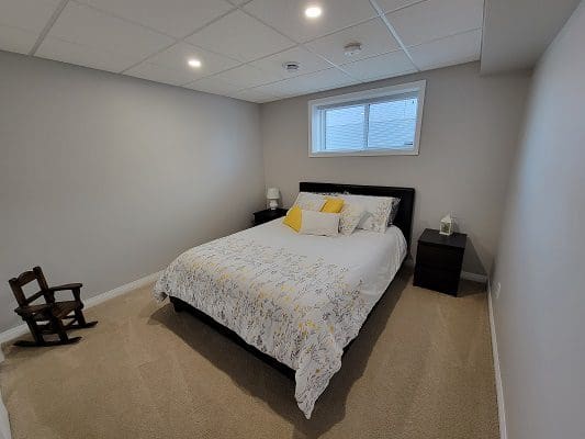 A bedroom with a white bed and yellow pillows.