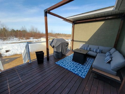 A deck with a couch and a fireplace.