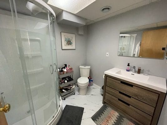 A bathroom with a toilet, shower and sink.