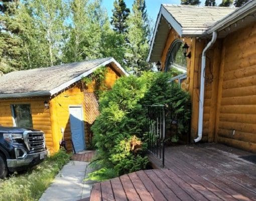 A house with a wooden deck and a car parked in front of it.