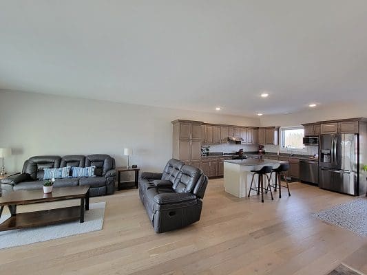 A living room with hardwood floors and a kitchen.