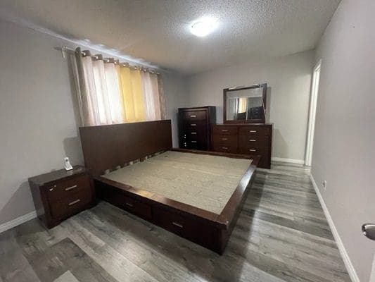 A bedroom with hardwood floors and a dresser.