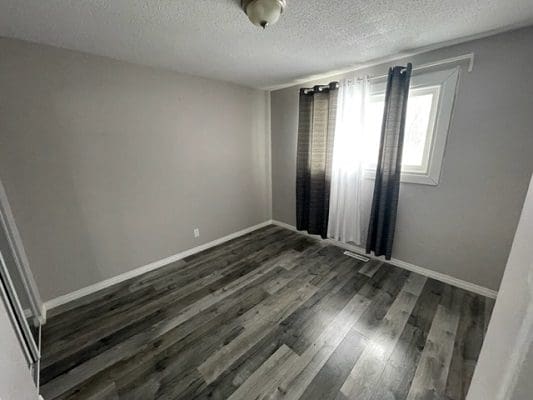 A room with gray wood floors and a window.