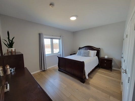A bedroom with hardwood floors and a bed.