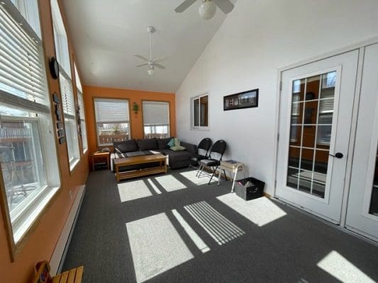 A living room with large windows and a ceiling fan.