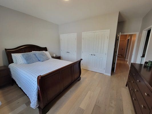 A bedroom with hardwood floors and a bed.