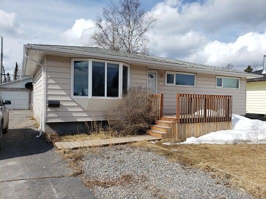 Off-White Starter Home With Wooden Front Porch and Garage