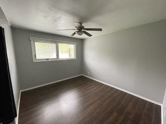 An empty room with hardwood floors and a ceiling fan.