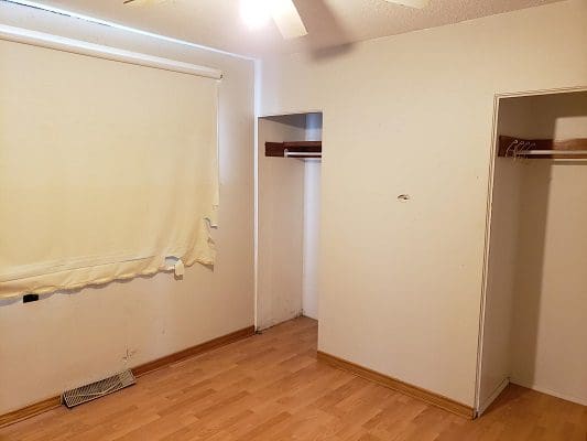 An empty room with hardwood floors and a ceiling fan.