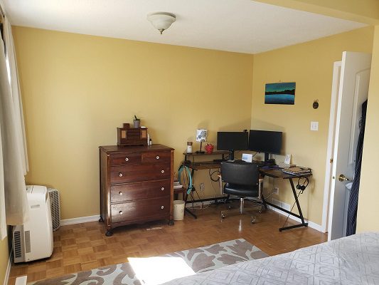 A bedroom with a desk and a window.