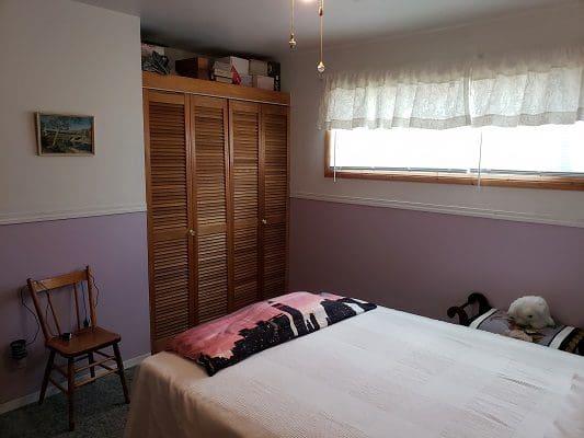 A bedroom with purple walls and a white bed.