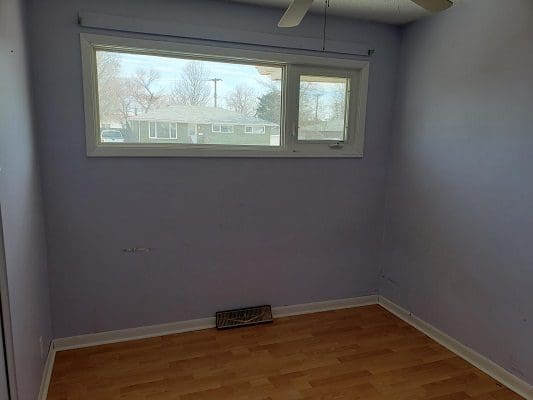 An empty room with purple walls and a ceiling fan.