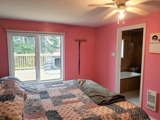 A bedroom with pink walls and a ceiling fan.