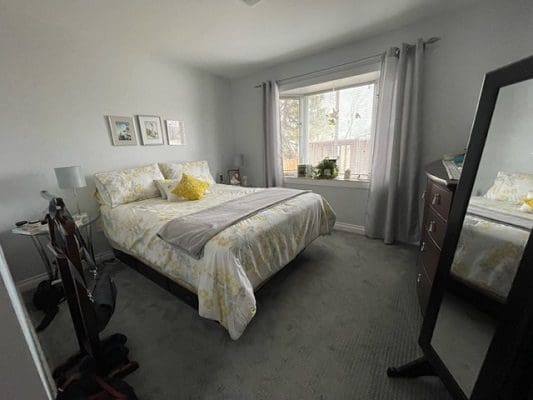 A bedroom with a bed, dresser and mirror.
