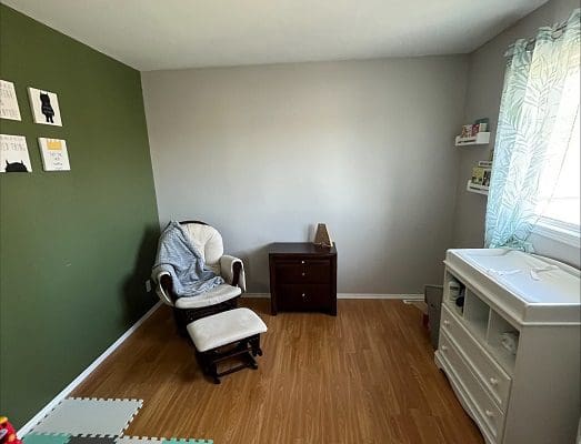 A baby room with green walls and a rocking chair.