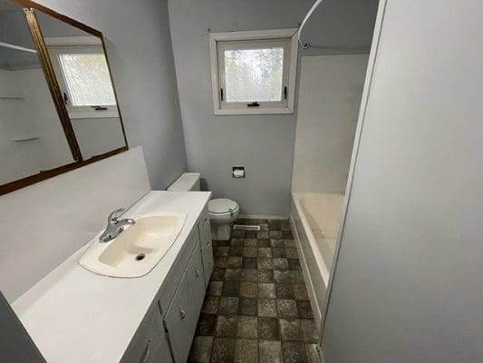 A bathroom with a sink, toilet and window.
