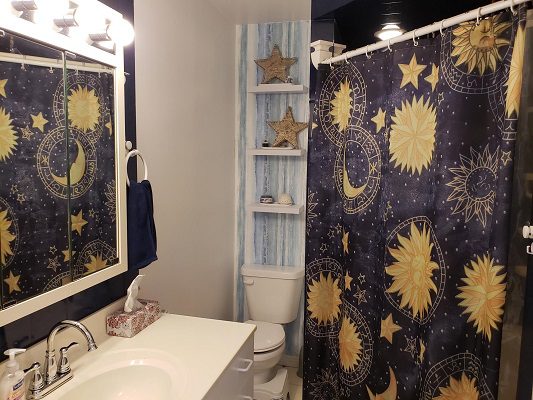 A bathroom with a blue and yellow star shower curtain.