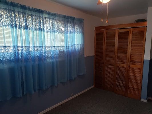 An empty room with blue curtains and a closet.