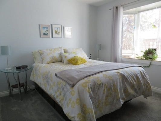 A bedroom with a yellow and white comforter and a window.