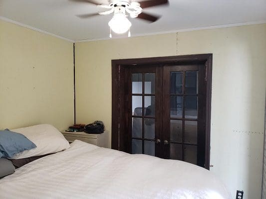 A bedroom with a ceiling fan and a door.