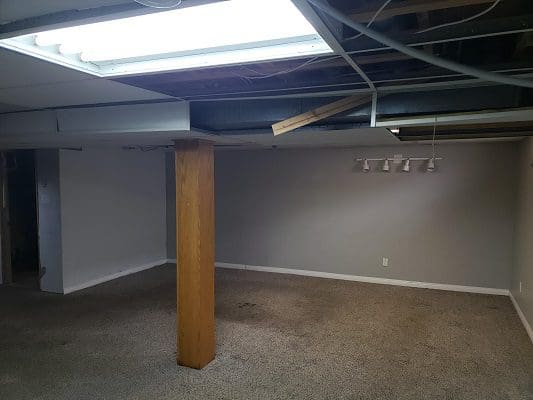 An empty basement with a light fixture and carpet.