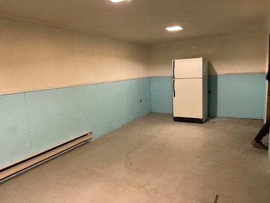 An empty room with blue walls and a refrigerator.