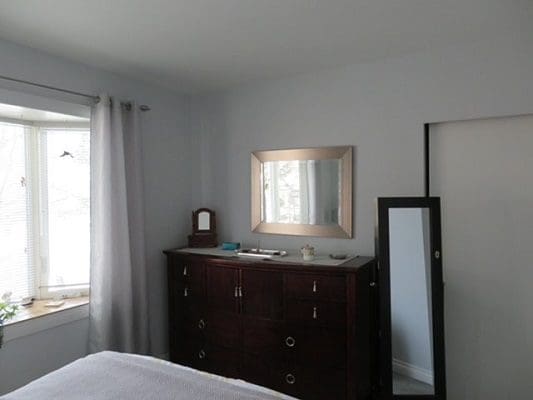 A bedroom with a dresser and mirror.
