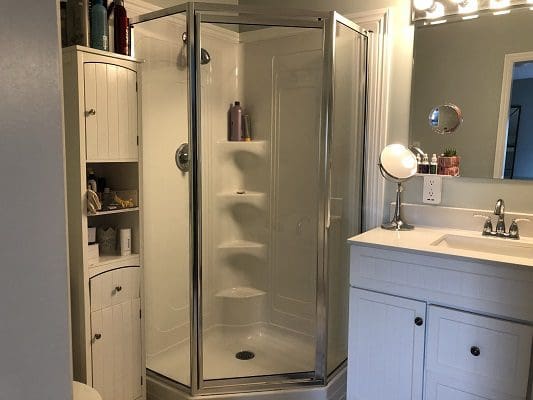 A white bathroom with a shower stall and sink.