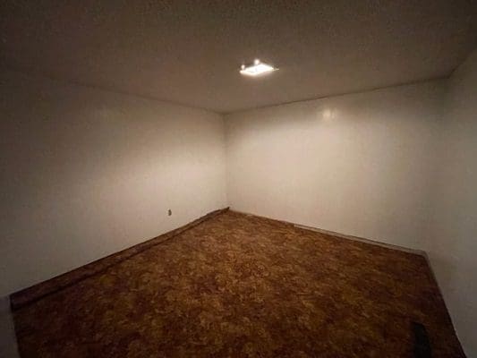 An empty room with wood floors and white walls.
