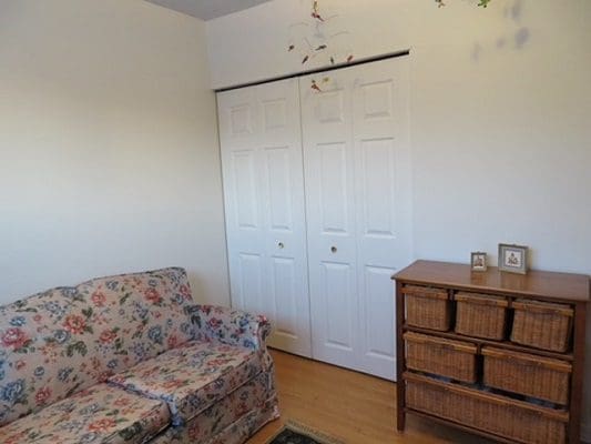 A small room with a floral couch and a dresser.