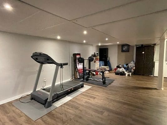 A gym room with a treadmill and other equipment.
