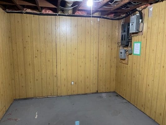 An empty room with wood paneling and an electrical outlet.